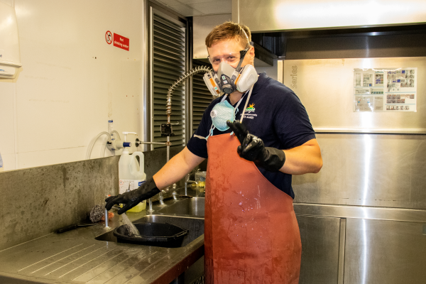 Team member cleaning a commercial kitchen.